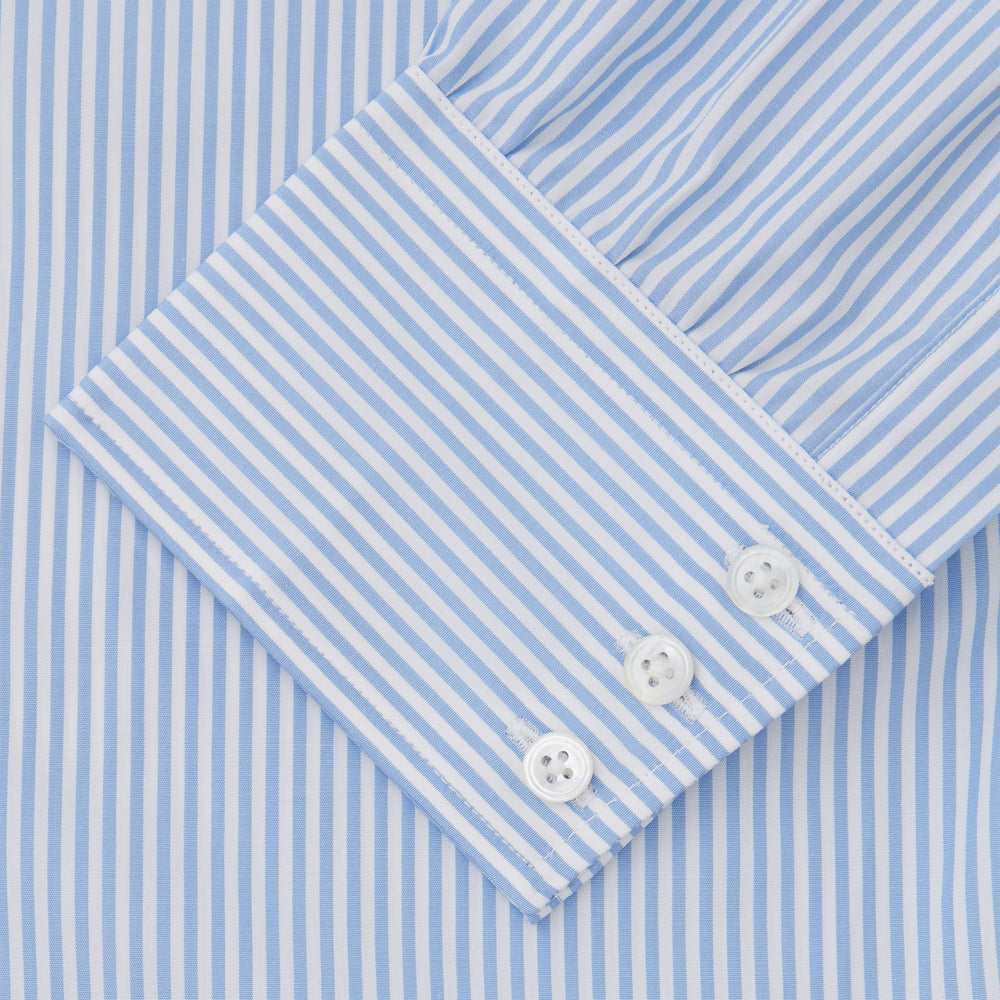 The Turnbull & Asser Light Blue Bengal Stripe Shirt features a classic T&A collar and 3-button cuffs, showcasing subtle British style in crisp white pinstripes, shown laid flat on a white background.