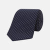View 1 of product The Turnbull & Asser White and Navy Spot Printed Silk Tie, shown rolled with its pointed end forward on a white background, is an elegant accessory that pairs perfectly with a crisp shirt for smart occasions.