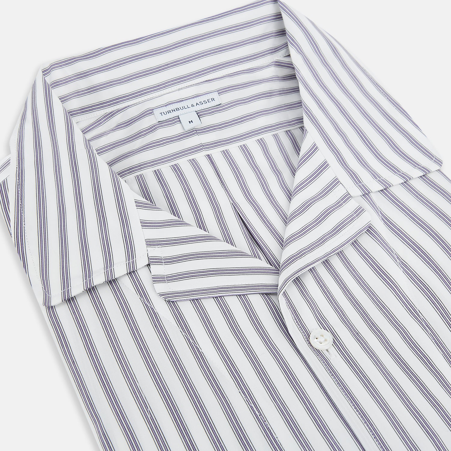 View 2 of product The Turnbull & Asser Purple Multi Stripe Quarzo Nightshirt features a collared, button-front design with a chest pocket and vertical white and light gray stripes, shown laid flat on a white background.