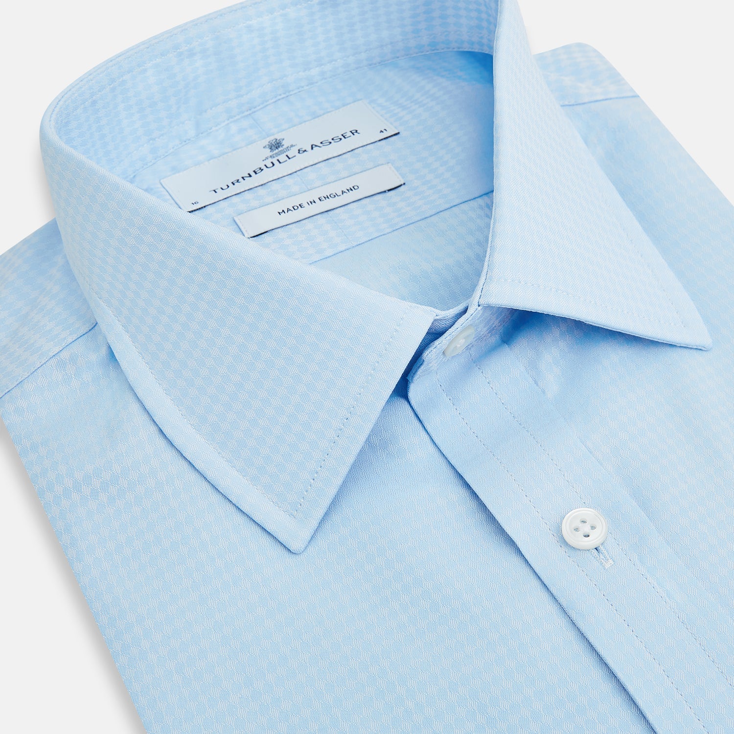 View 2 of product The Pale Blue Rhombus Mayfair Shirt by Turnbull & Asser features long sleeves, a classic collar, white buttons, and buttoned cuffs, shown laid flat on a white background.