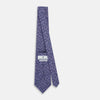 View 4 of product The Turnbull & Asser Lilac Paisley Silk Tie, crafted in England, features a blue paisley pattern on a lilac background and is shown rolled up against a white surface.
