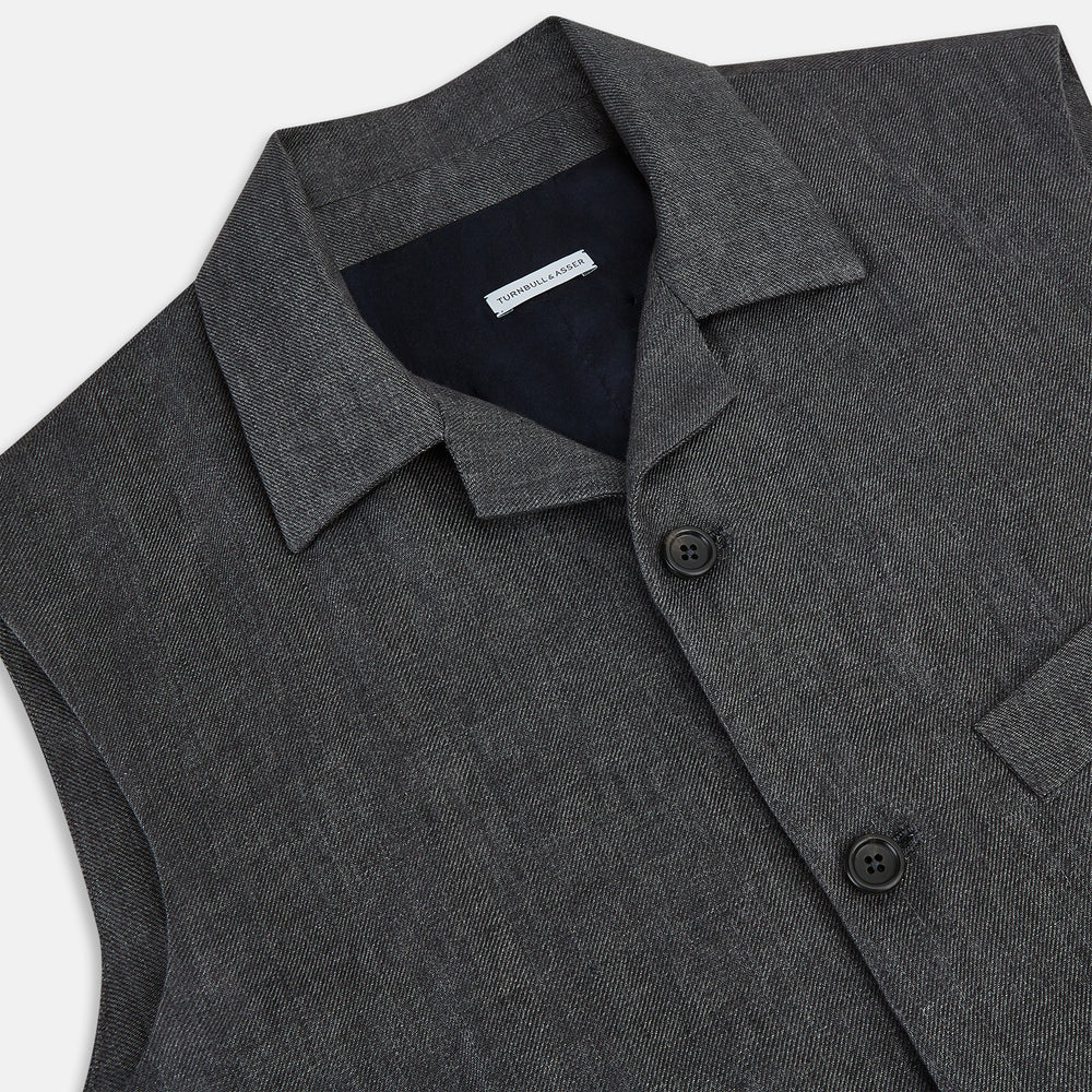 The Turnbull & Asser Ash Collared Linen Waistcoat is a sleeveless dark gray piece with a button-down front, two zippered side pockets, and a small chest pocket, shown against a plain white background.