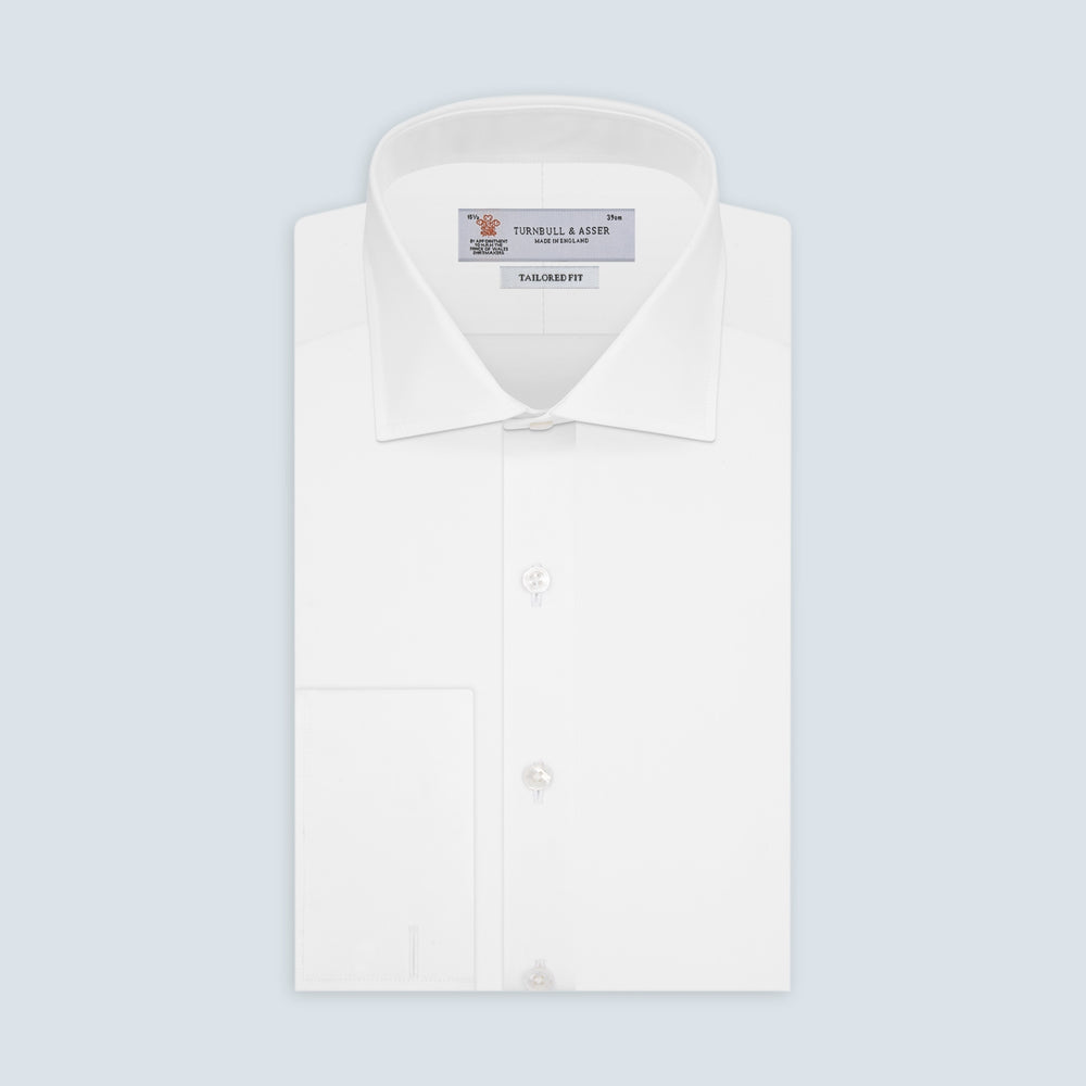The Turnbull & Asser Tailored Fit Two-Fold 120 White Cotton Shirt features a Kent collar, double cuffs, and button-down front, displayed neatly folded against a light blue background.