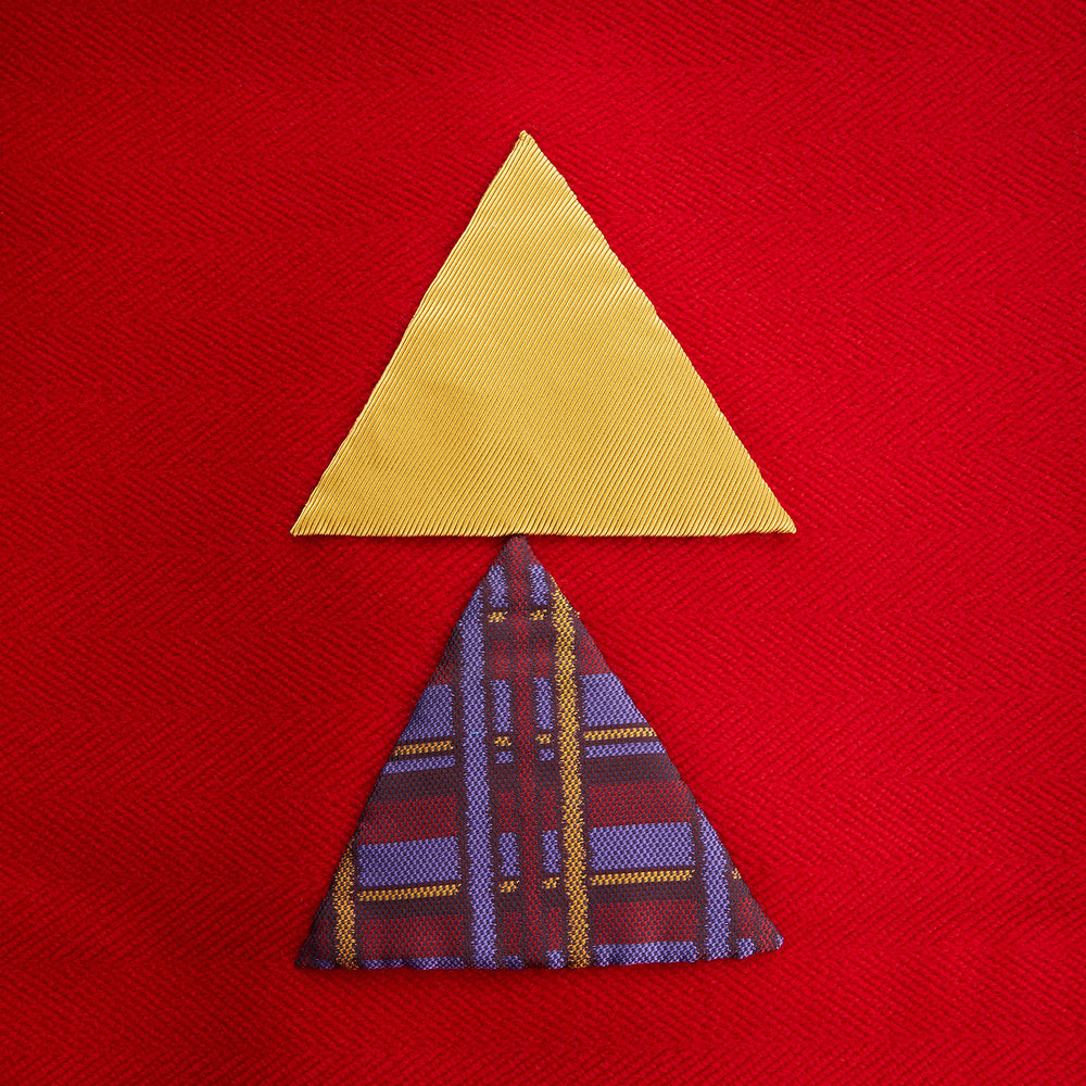 The Turnbull & Asser Red Applique Hand Stitched Lambswool Blanket features black-stitched edges and handsewn tie silk patches, including a yellow triangle and plaid triangle arranged to form a stylized fish.