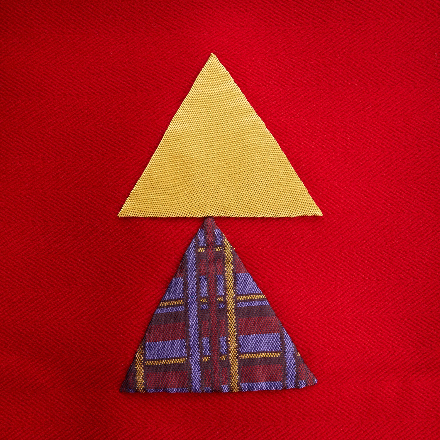 View 5 of product The Turnbull & Asser Red Applique Hand Stitched Lambswool Blanket features black-stitched edges and handsewn tie silk patches, including a yellow triangle and plaid triangle arranged to form a stylized fish.
