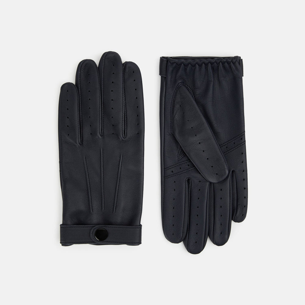A pair of Navy Hairsheep Leather Touchscreen Driving Gloves by Turnbull & Asser is displayed, one palm up and one palm down. Crafted in Britain, the gloves feature vent holes, decorative stitching, and a snap button closure.