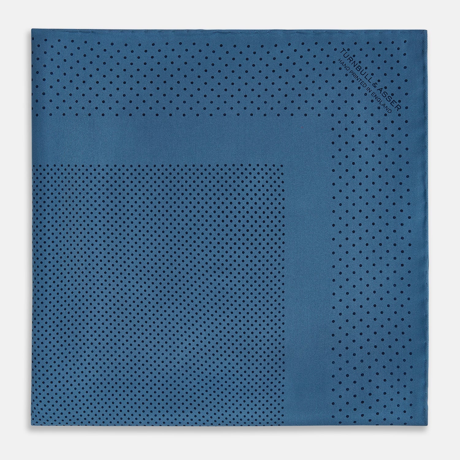 View 3 of product The Blue Dot Silk Pocket Square by Turnbull & Asser features small black polka dots on blue silk and is made in England. The image shows it neatly folded, with a corner turned down to display both sides.