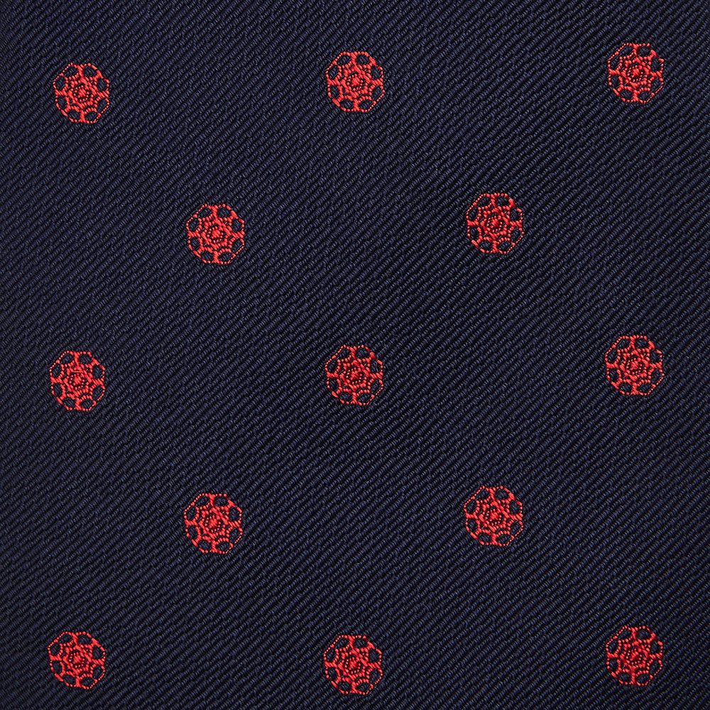 The EMBLEM SPOT NAVY TULIP TIE by Turnbull & Asser features a navy base with red circle motifs, neatly rolled on a white background—an essential accessory for refined style.