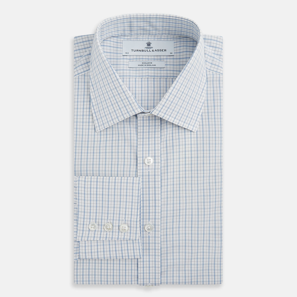 The Turnbull & Asser Sky Blue Combination Graph Check Mayfair Shirt features long sleeves, a pointed collar, buttoned cuffs, and a blue and white check pattern that showcases British craftsmanship. Displayed on a white background.