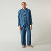 View 1 of product A person stands barefoot against a plain background, wearing the Teal Linen Modern Pyjama Set from Turnbull & Asser.