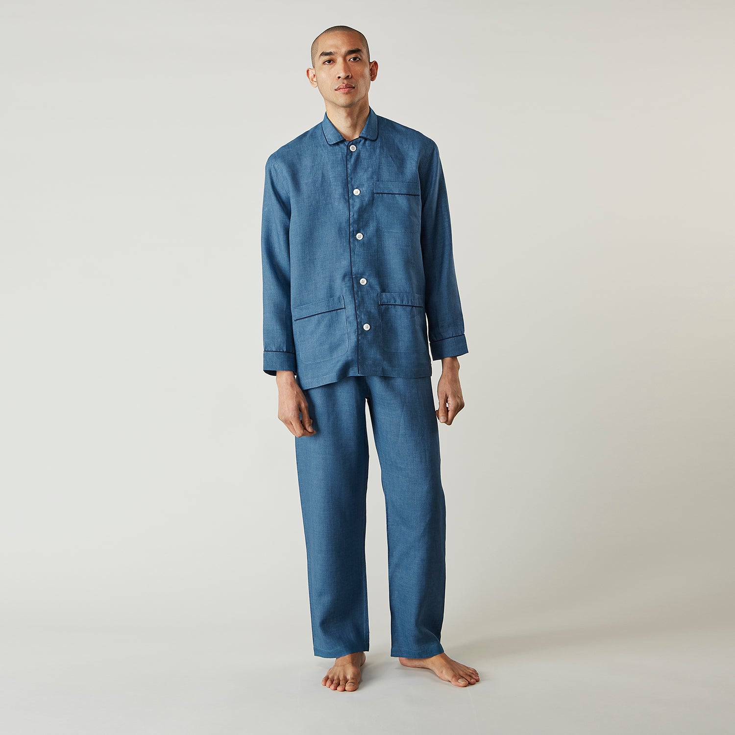 View 1 of product A person stands barefoot against a plain background, wearing the Teal Linen Modern Pyjama Set from Turnbull & Asser.