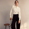 View 10 of product The Cream Silk Tailored Bianca Shirt by Turnbull & Asser features long sleeves, a pointed collar, and curved hem in soft-touch peace silk with a tailored fit. Shown laid flat on a white background.