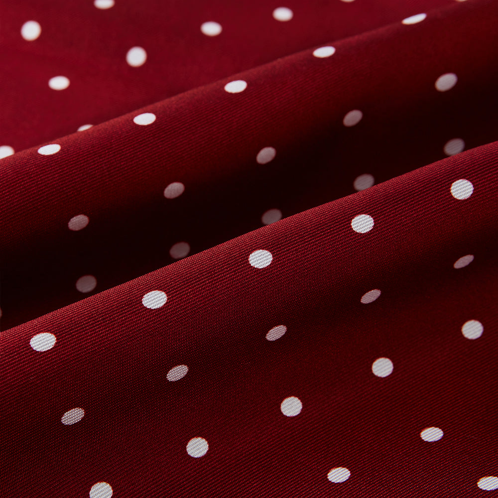 The Burgundy and White Spotted Silk Scarf by Turnbull & Asser features a gradient of white polka dots, short fringed edges, and the brand's name near the ends—a timeless classic foulard.