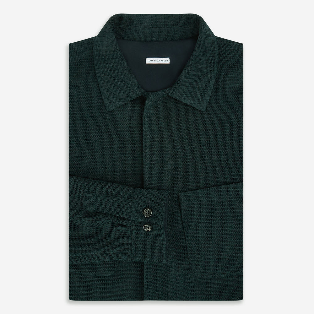 The Forest Green Greenwich Knitted Overshirt by Turnbull & Asser, crafted from Italian wool, features long sleeves, a collar, front buttons, and two chest pockets—one flap, one open—shown on a white background.