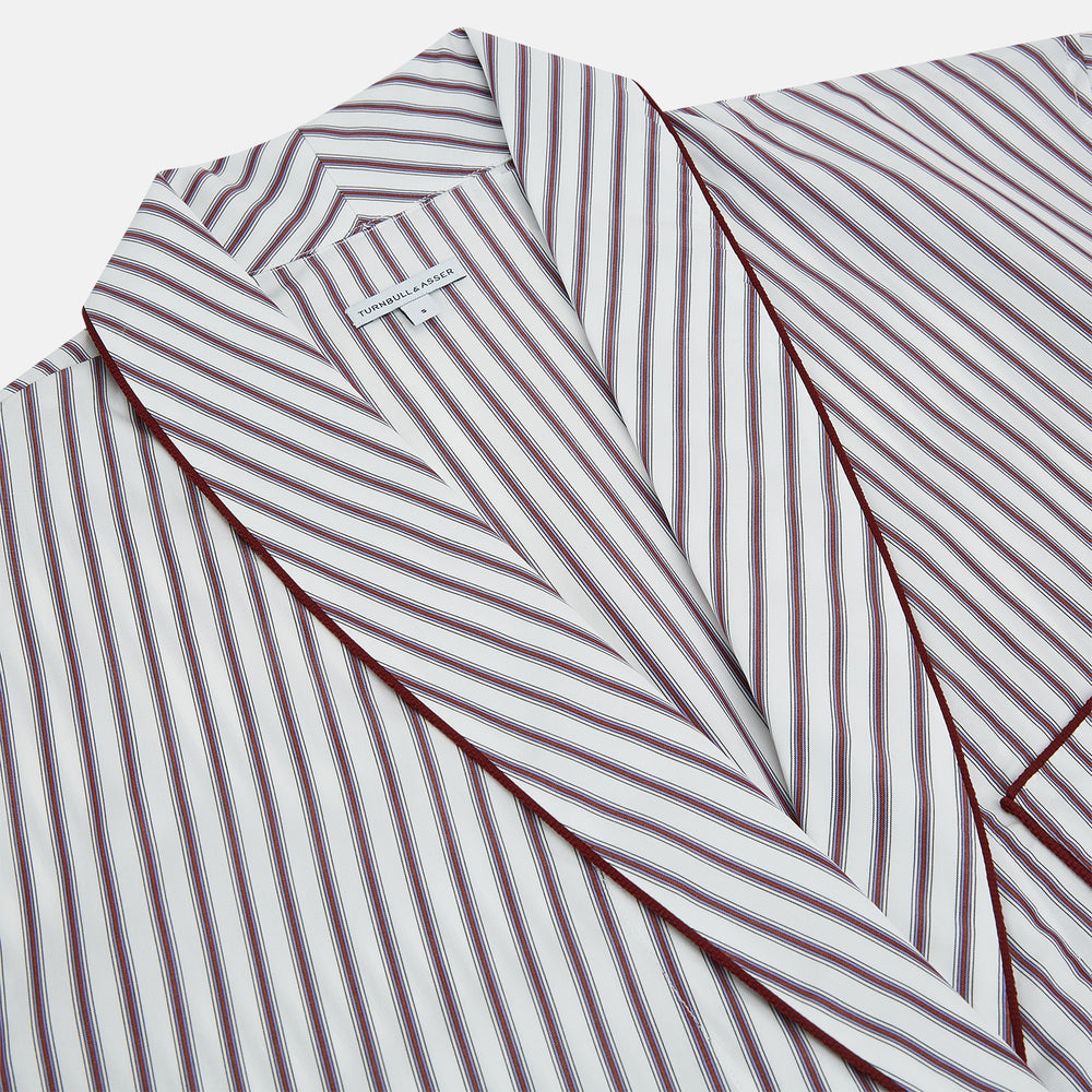 The Burgundy Multi Stripe Winston Gown by Turnbull & Asser features long sleeves, a shawl collar, waist belt, three pockets, and red piping accents for a classic Churchill-inspired touch.