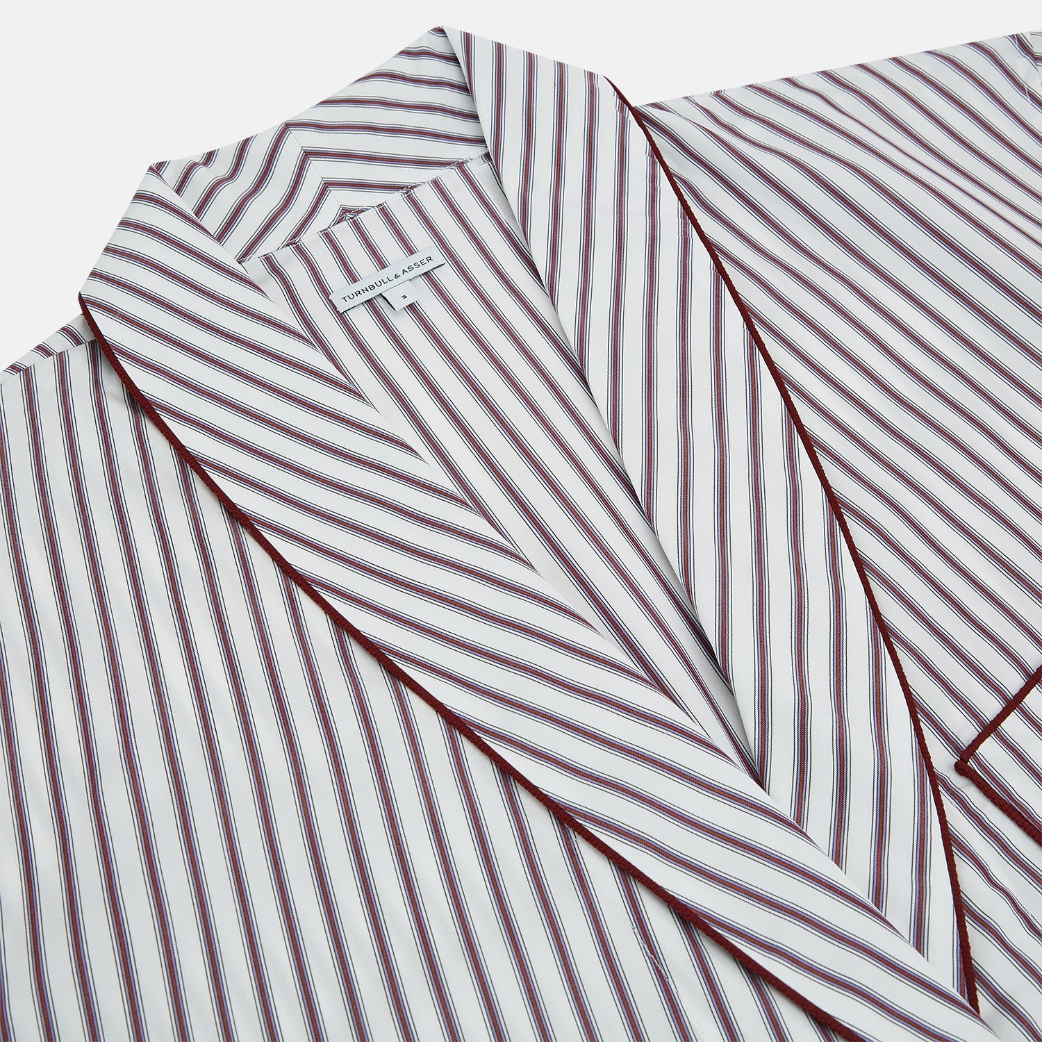 View 2 of product The Burgundy Multi Stripe Winston Gown by Turnbull & Asser features long sleeves, a shawl collar, waist belt, three pockets, and red piping accents for a classic Churchill-inspired touch.