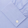View 6 of product The Turnbull & Asser Blue Hairline Stripe Shirt features a T&A collar, 3-button cuffs, and white buttons. Made from light blue cotton with subtle stripes, it’s neatly folded with the label visible inside the collar on a plain white background.
