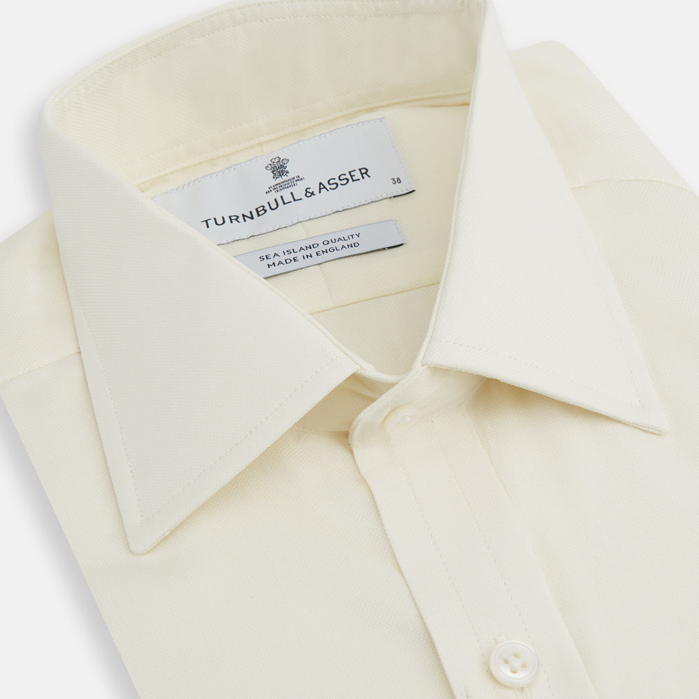 The Turnbull & Asser Tomorrow Never Dies Cream Cotton Hamburg Shirt, as seen on James Bond, features a long sleeve, button-down front, and collar. It's laid flat on a white background.