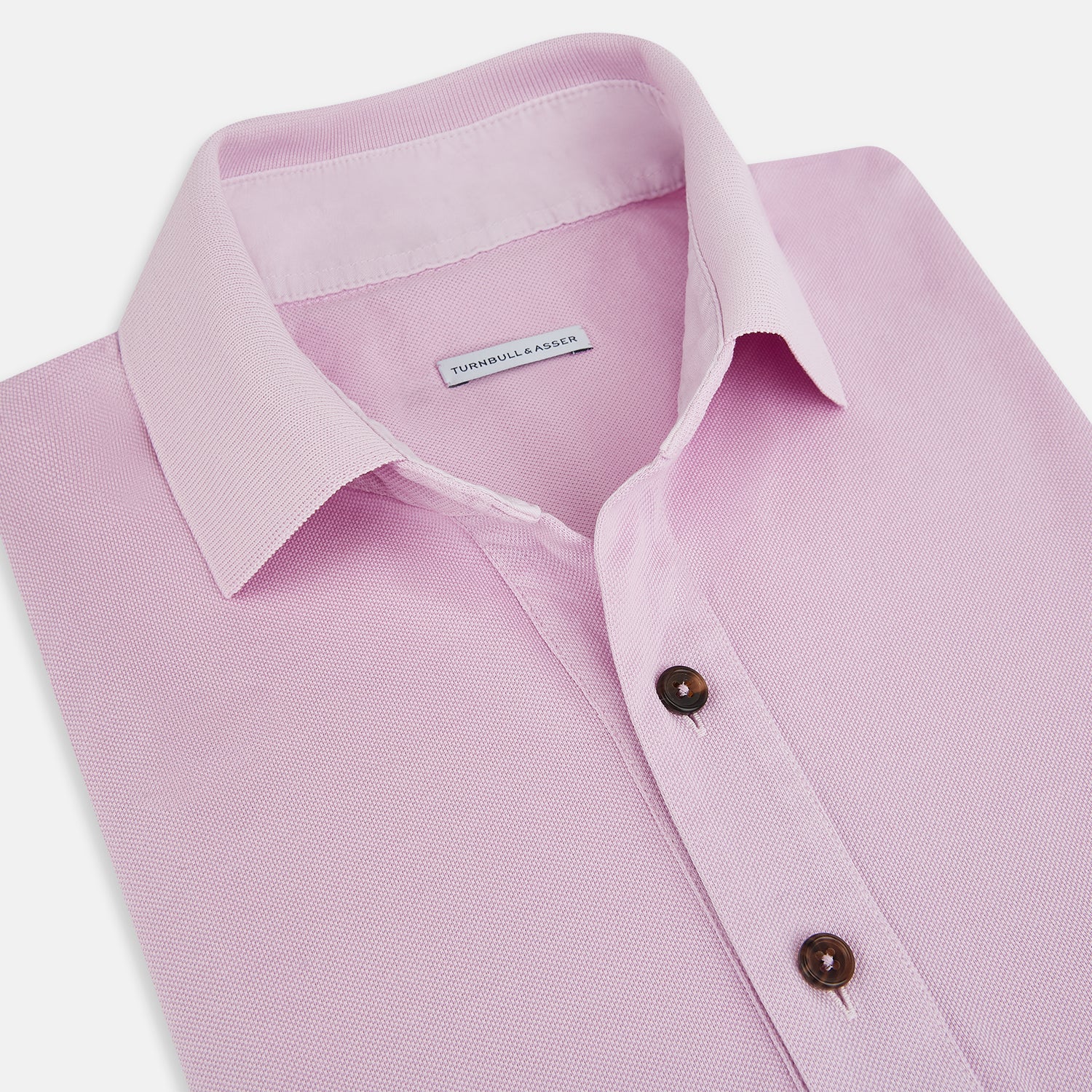 View 2 of product The Turnbull & Asser Pink Polo Shirt is a men's cotton polo with short sleeves, a collar, three dark buttons, and a chest pocket with a button, shown laid flat on a white background.