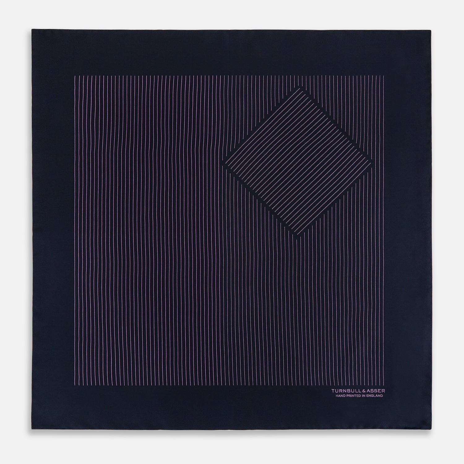 View 4 of product A navy silk pocket square with thin, even purple stripes and hand-rolled edges from Turnbull & Asser, featuring "Turnbull & Asser Hand Printed in England" printed in the corner.