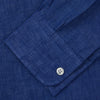 View 6 of product A man faces forward with a neutral expression, hands in his pockets, wearing the Turnbull & Asser Plain Indigo Linen Weekend Fit Shirt with a stand collar, styled with dark pants and black shoes against a plain light background.