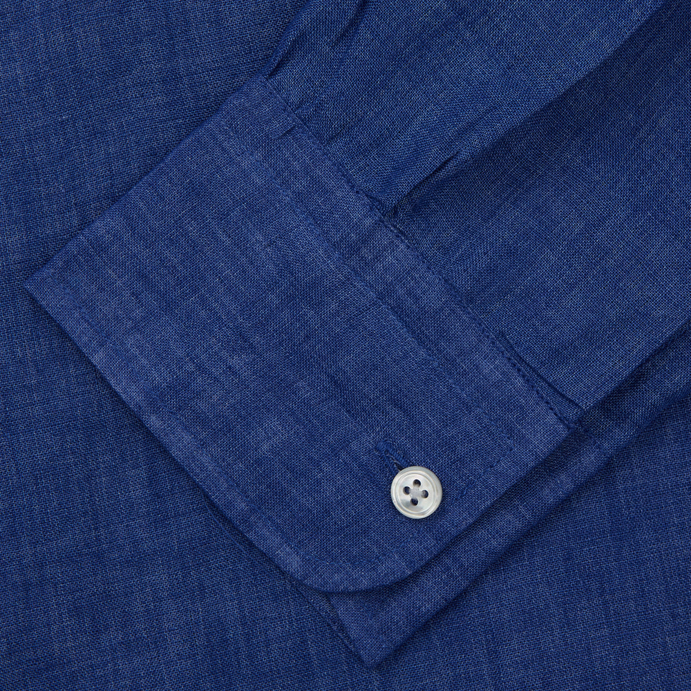 A man faces forward with a neutral expression, hands in his pockets, wearing the Turnbull & Asser Plain Indigo Linen Weekend Fit Shirt with a stand collar, styled with dark pants and black shoes against a plain light background.