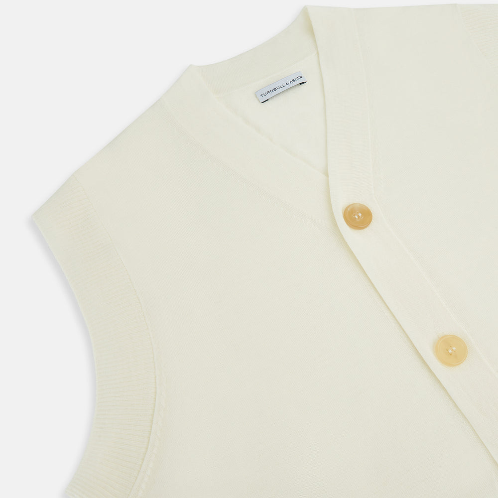 The Ecru Fine Merino V-Neck Sleeveless Cardigan from Turnbull & Asser features a front button closure with five light brown buttons and two pockets. Soft, lightweight, and ideal for gentlemanly layering in cooler seasons.