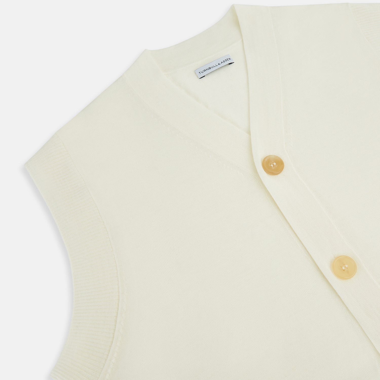 View 2 of product The Ecru Fine Merino V-Neck Sleeveless Cardigan from Turnbull & Asser features a front button closure with five light brown buttons and two pockets. Soft, lightweight, and ideal for gentlemanly layering in cooler seasons.