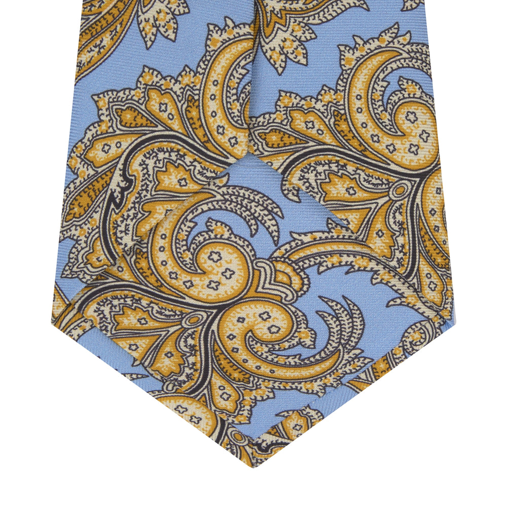 The Turnbull & Asser GGT92000 3062 06 OS is a rolled-up necktie with an intricate blue and yellow paisley pattern on a light blue background—a stylish accessory for any wardrobe.