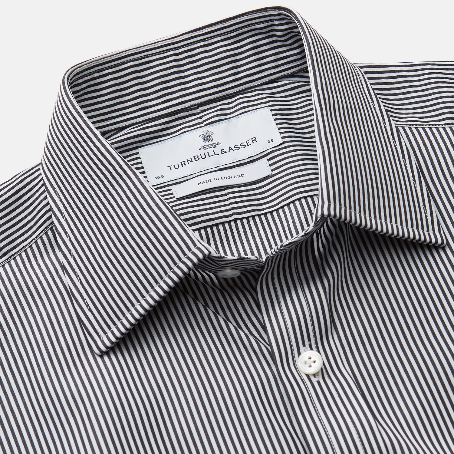 View 2 of product The Turnbull & Asser Black Candy Stripe Cotton Regular Fit Mayfair Shirt features long sleeves, a T&A collar, white buttons, and thin black stripes, displayed on a plain white background.