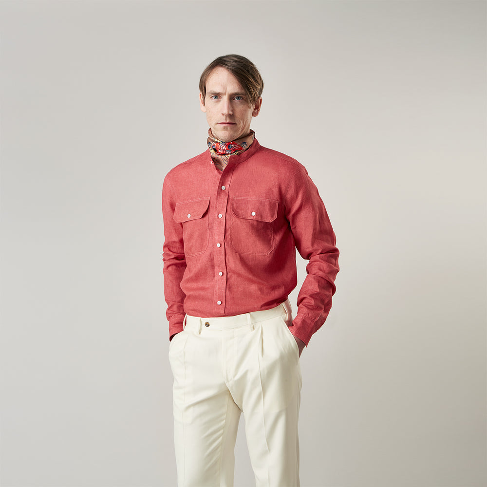 The Turnbull & Asser Plain Red Linen Weekend Fit Shirt with Stand Collar features long sleeves, a button-up front, and two buttoned-flap chest pockets. It is shown neatly laid flat on a plain light background.