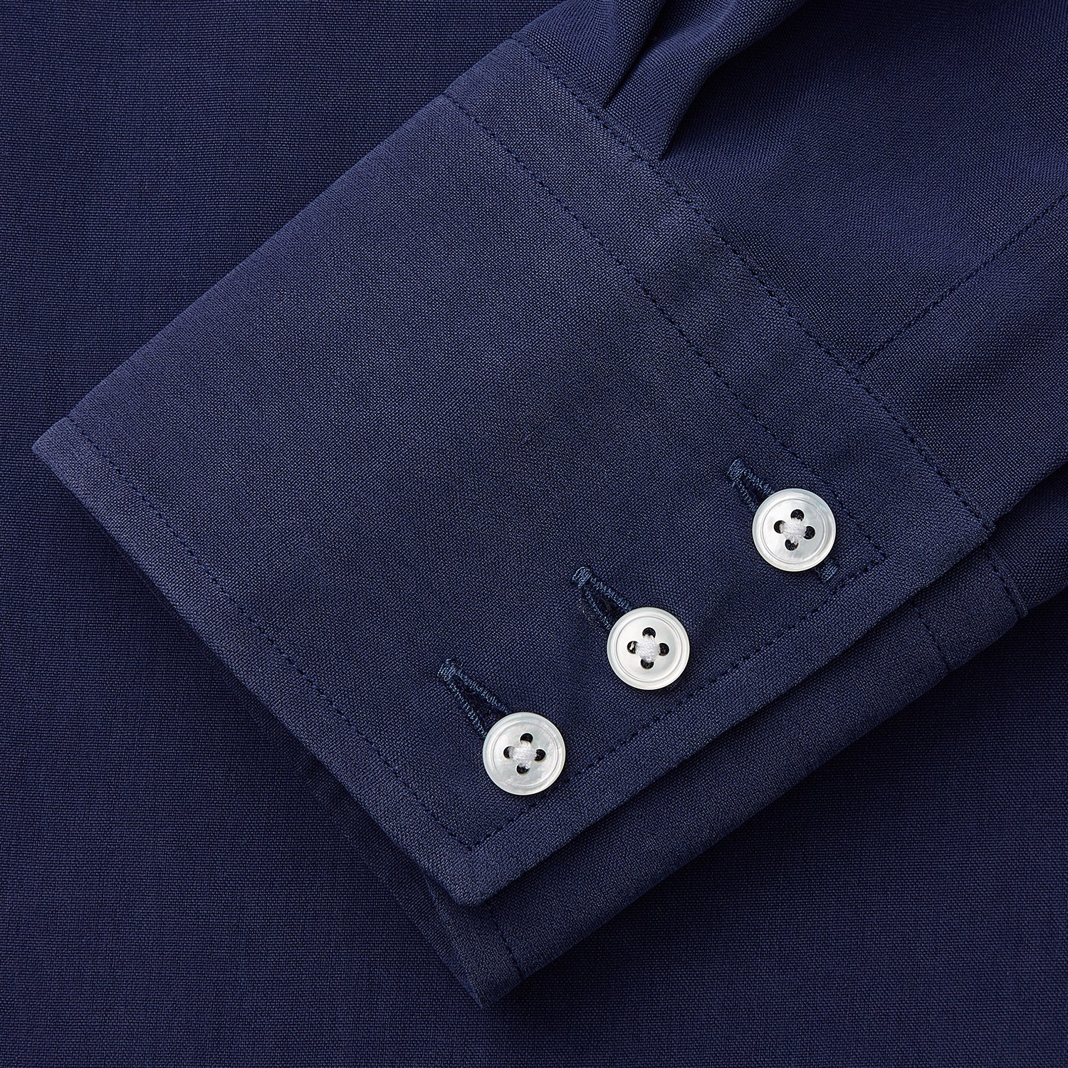 View 4 of product The Turnbull & Asser Blue Soft-touch Silk Lauren Shirt is a navy, long-sleeve button-up with an Igret stand collar, white buttons, curved hem, relaxed fit, and elongated body for a modern look, shown laid flat on a white background.