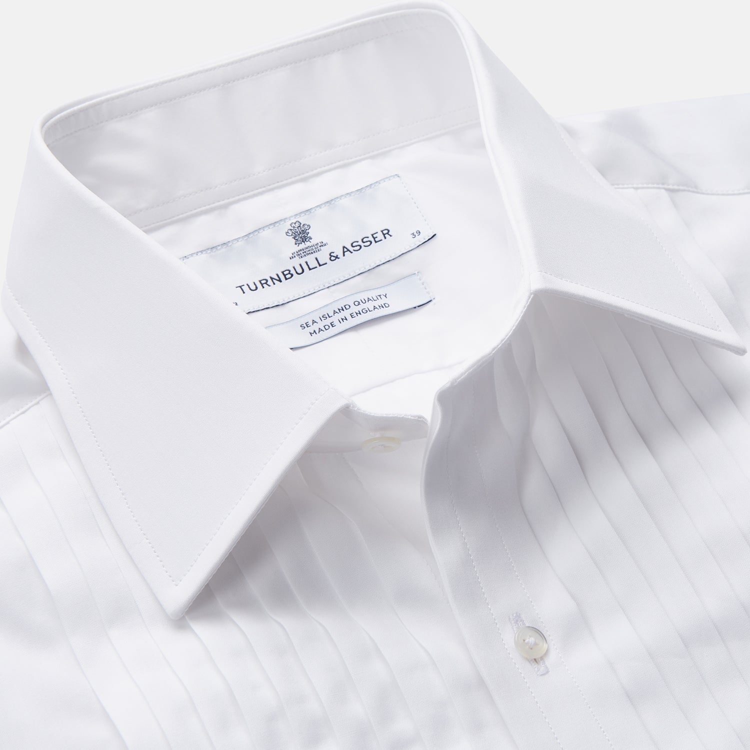 View 2 of product The Turnbull & Asser White Pleated Cotton Dress Shirt features a T&A collar and double cuffs, shown laid flat on a white background.