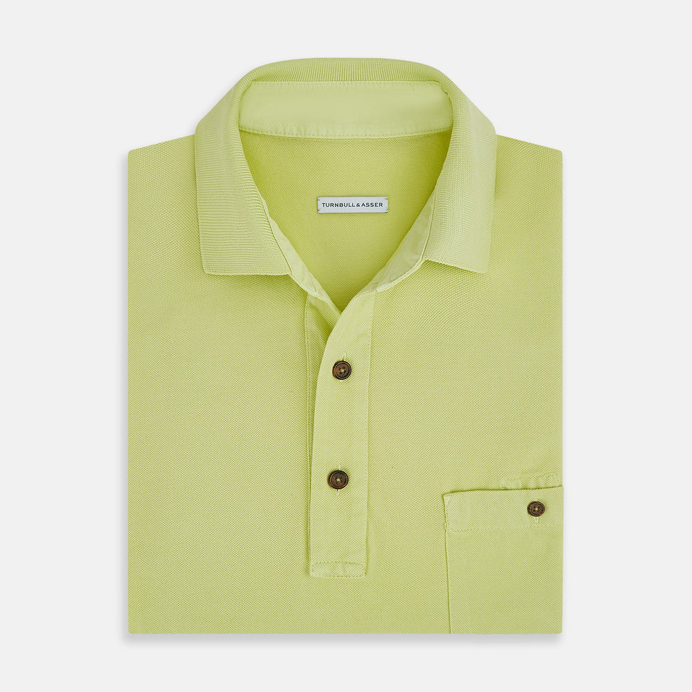 The Turnbull & Asser Lime Green Polo Shirt features a cotton jersey build, short sleeves, a collar, three brown buttons on the placket, and a chest pocket with a button. Shirt shown laid flat on a white background.