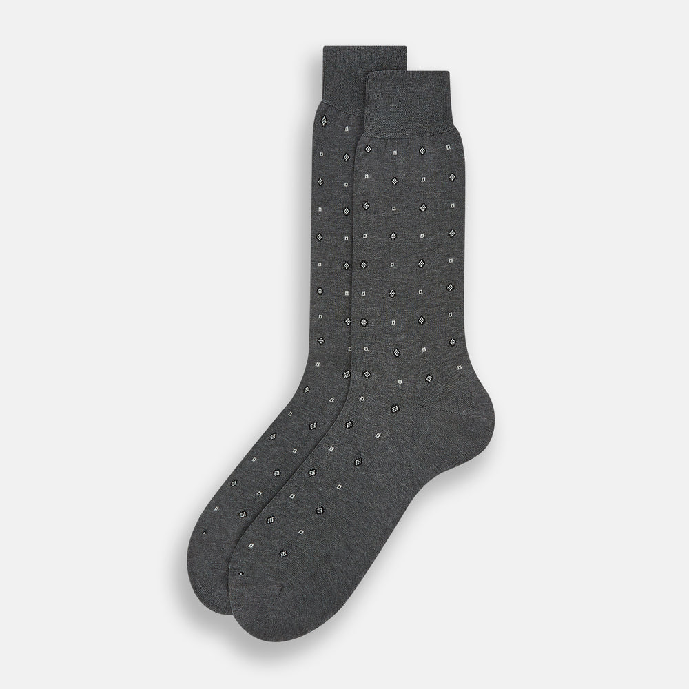 The Grey Patterned Mid-Length Socks by Turnbull & Asser are crafted from soft Egyptian cotton, with a ribbed cuff and small white diamond shapes on a grey background.
