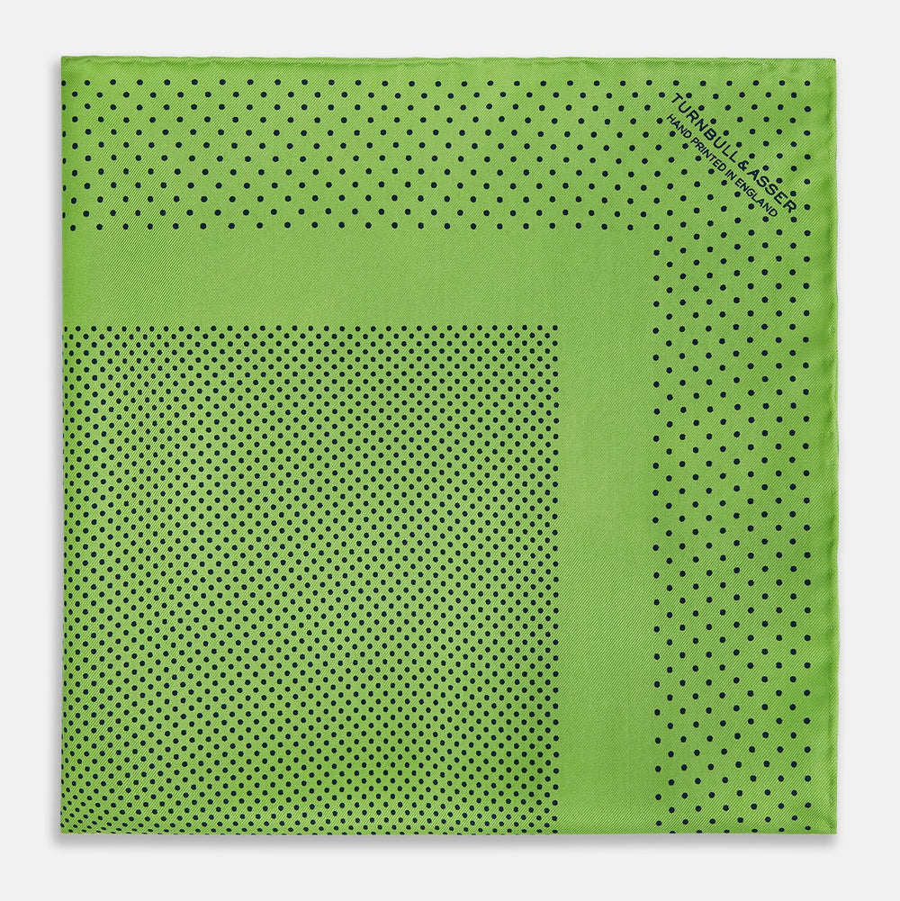 The Turnbull & Asser Kelly Green Dot Silk Pocket Square features small black polka dots and is shown neatly folded to showcase both its front and inner sides.