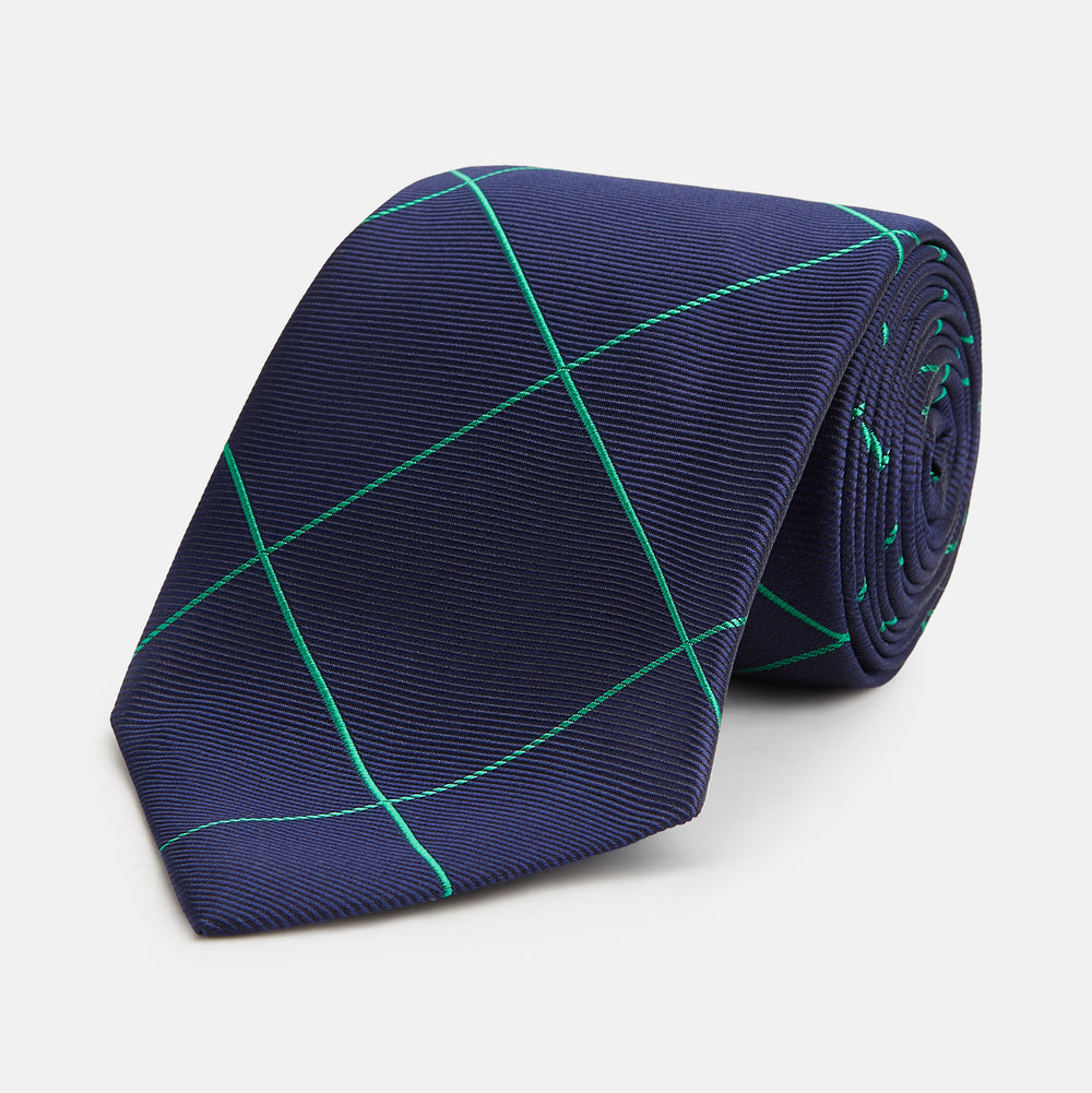 The Turnbull & Asser Green and Navy Window Pane Silk Tie features a subtle ribbed texture with a diagonal green grid pattern, inspired by archival designs—a stylish choice for modern office attire.