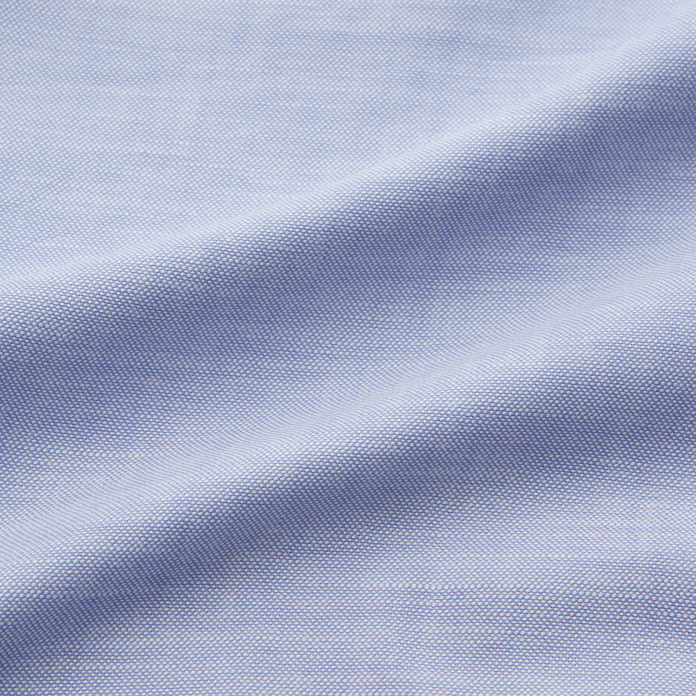The Turnbull & Asser Pale Blue Weekend Fit Hayne Shirt features a Dorset collar, white buttons, and 1-button cuffs. This casual, long-sleeve button-down is displayed laid flat on a white background.