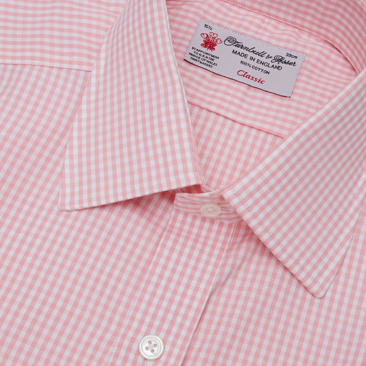 View 5 of product The Turnbull & Asser Light Pink Gingham Check Shirt features a classic T&A collar, 3-button cuffs, and white buttons, neatly folded on a plain white background.