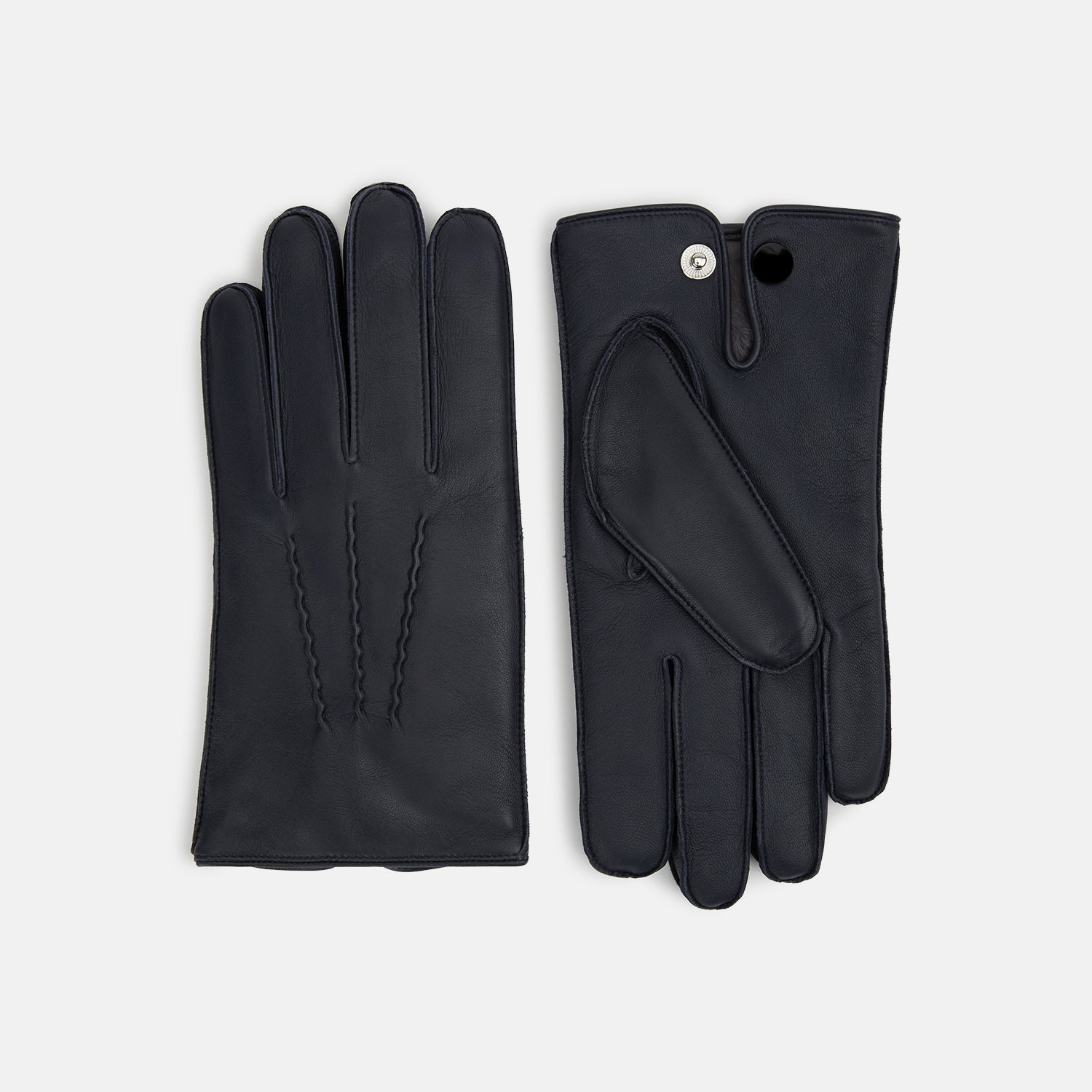 View 1 of product A pair of Turnbull & Asser Navy/Grey Fur-Lined Hairsheep Leather Touchscreen Gloves is displayed on a light background, with one glove showing the palm and the other the back, both featuring simple stitched details and a wrist button closure.