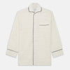 View 5 of product The Cream Pattern Cotton Blend Quin Pyjama Set by Turnbull & Asser features cream stripes, a long-sleeve button-up camp collar shirt with a chest pocket and black piping, and matching drawstring pants.