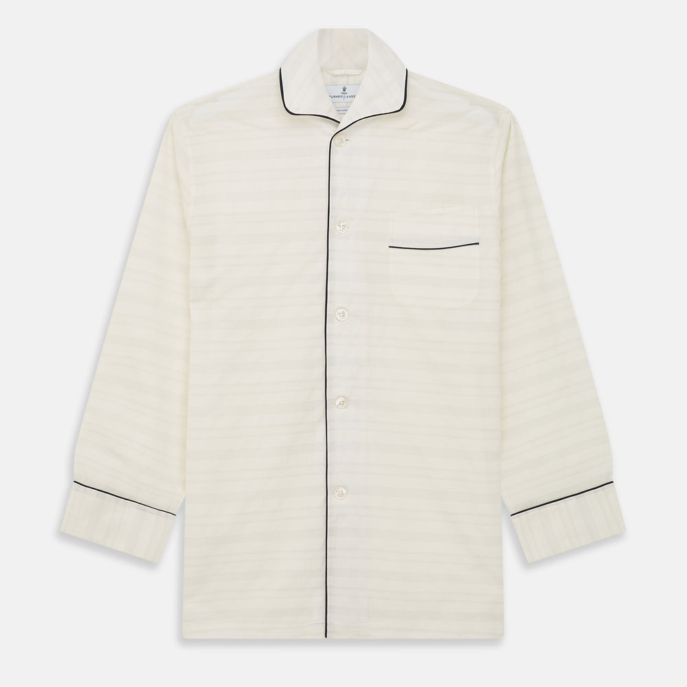 The Cream Pattern Cotton Blend Quin Pyjama Set by Turnbull & Asser features cream stripes, a long-sleeve button-up camp collar shirt with a chest pocket and black piping, and matching drawstring pants.