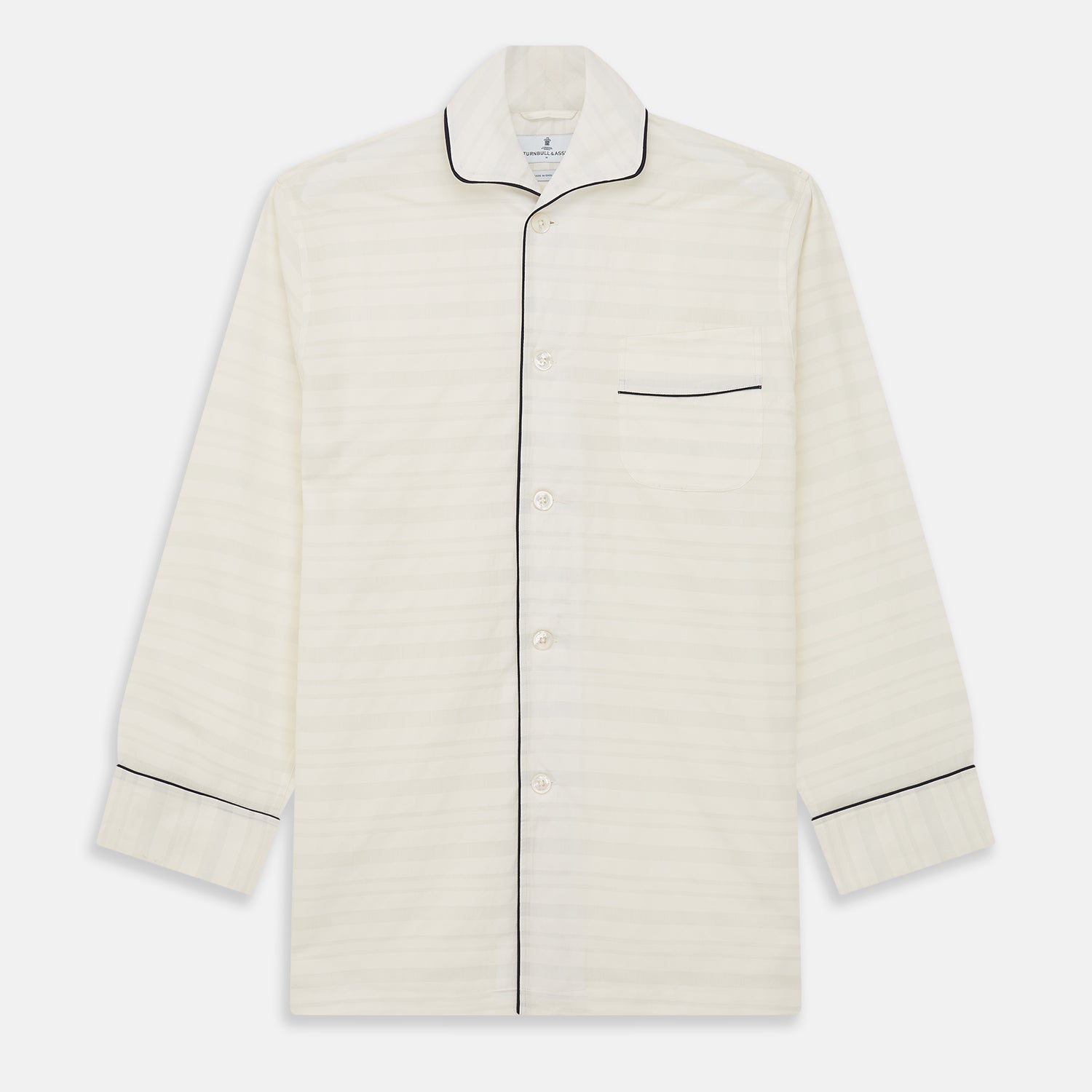 View 5 of product The Cream Pattern Cotton Blend Quin Pyjama Set by Turnbull & Asser features cream stripes, a long-sleeve button-up camp collar shirt with a chest pocket and black piping, and matching drawstring pants.