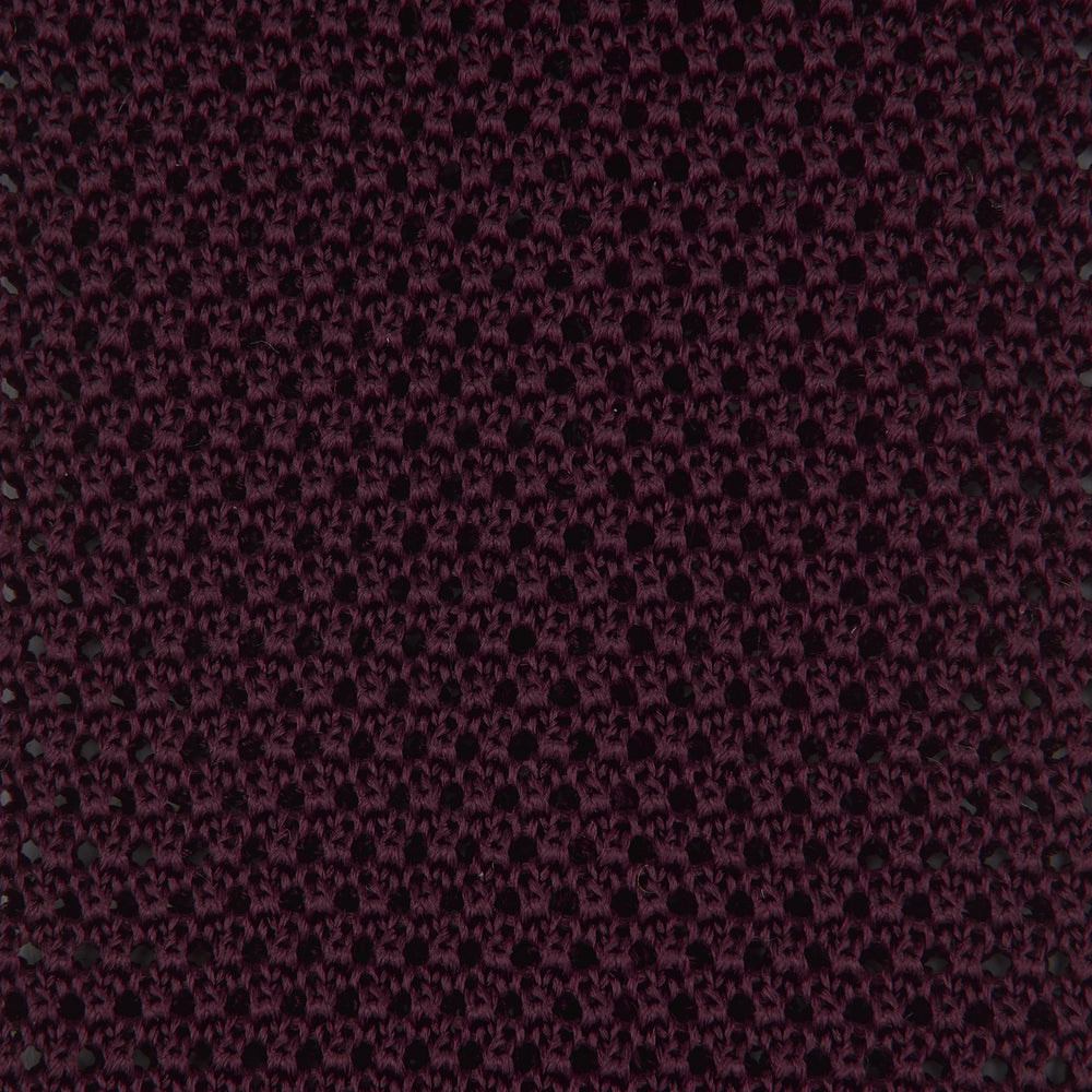 The Turnbull & Asser MTIE011-ZAI003 TIES 7.5CM is a plain burgundy tie shown rolled on a white background, featuring straight edges and textured knit—ideal for the modern gentleman’s versatile wardrobe.