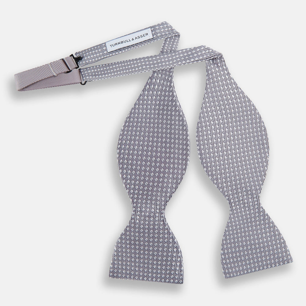 The Turnbull & Asser Silver and White Square Silk Bow Tie features a subtle geometric pattern, ideal for formalwear, and is displayed against a plain white background.