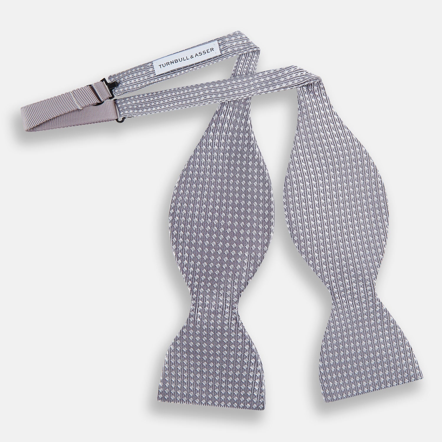View 2 of product The Turnbull & Asser Silver and White Square Silk Bow Tie features a subtle geometric pattern, ideal for formalwear, and is displayed against a plain white background.