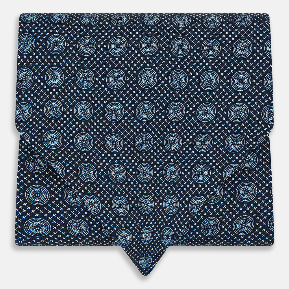 The Turnbull & Asser Navy Medallion Silk Cravat features a white geometric and circular pattern, its classic design and rich navy hue echoing refined British elegance.