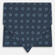 The Turnbull & Asser Navy Medallion Silk Cravat features a white geometric and circular pattern, its classic design and rich navy hue echoing refined British elegance.