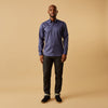 View 6 of product The Blue Piece Dyed Weekend Fit Suffolk Shirt by Turnbull & Asser features a button-down Dorset collar, chest pocket, white buttons, and long sleeves in classic navy, laid flat against a white background.
