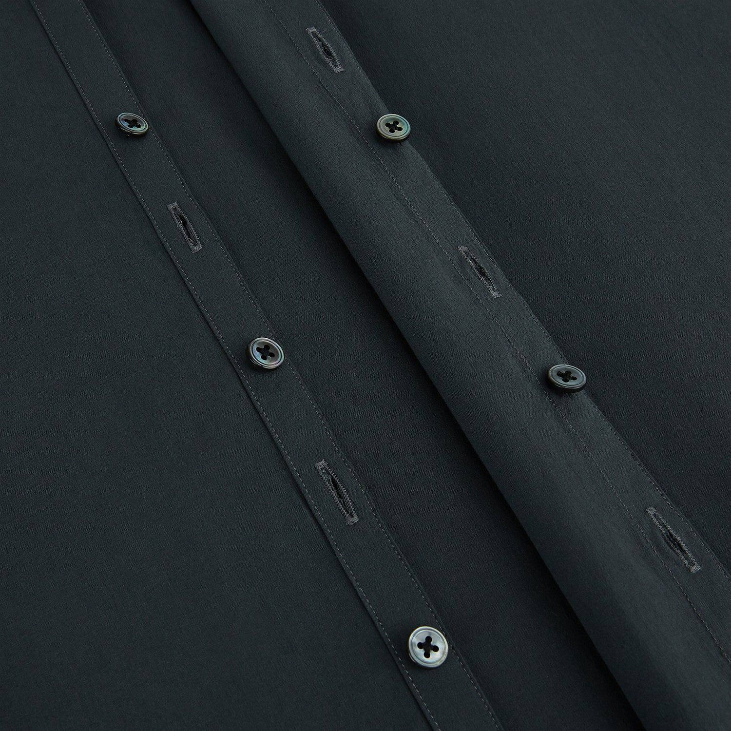 View 7 of product The Charcoal Windsor Shirt by Turnbull & Asser is a black, long-sleeve button-up with a pointed Windsor collar, buttoned cuffs, and a straight hem, shown flat on a white background.